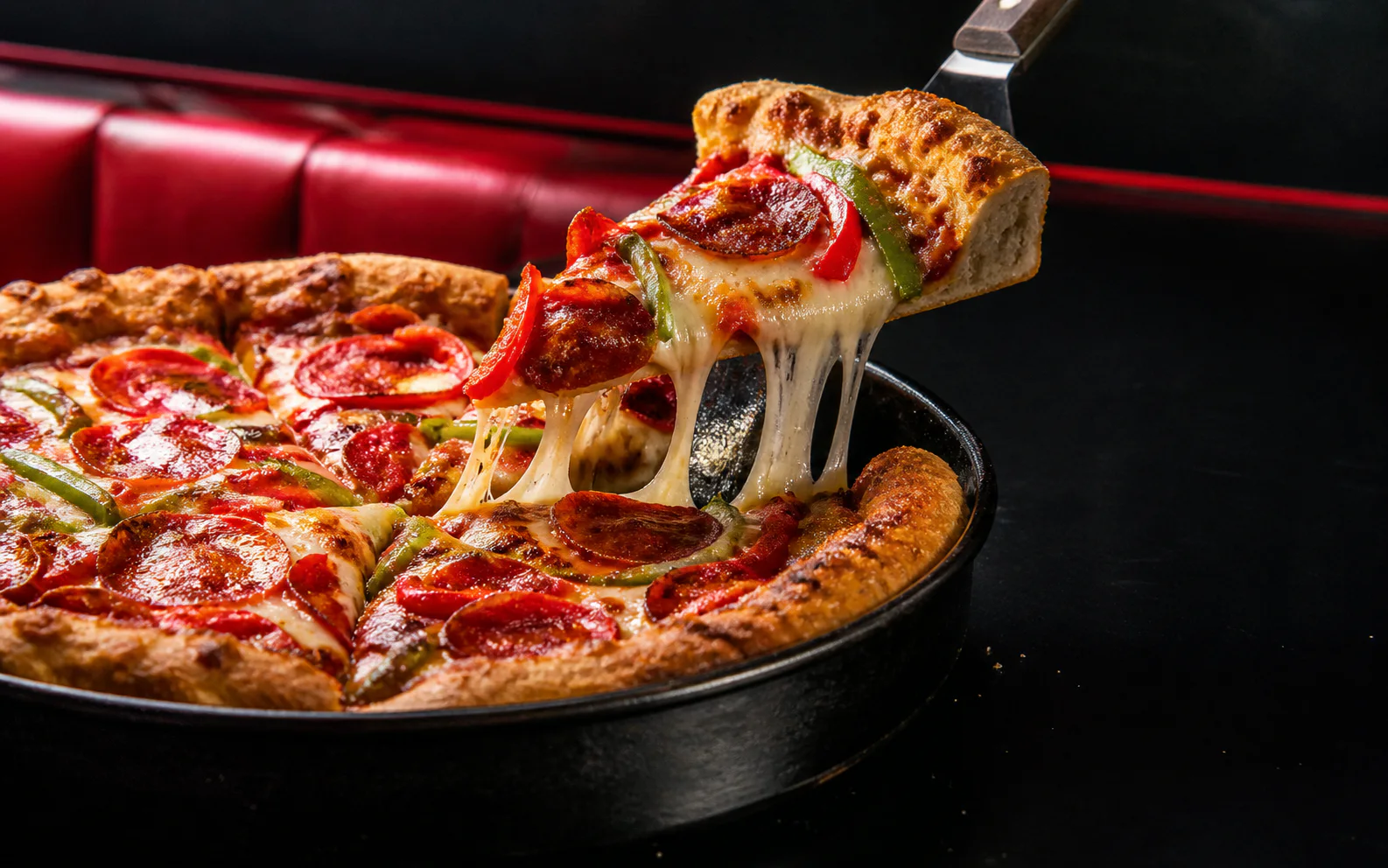 Pan Pizza mit angehobenem Stück und geschmolzenem Käse