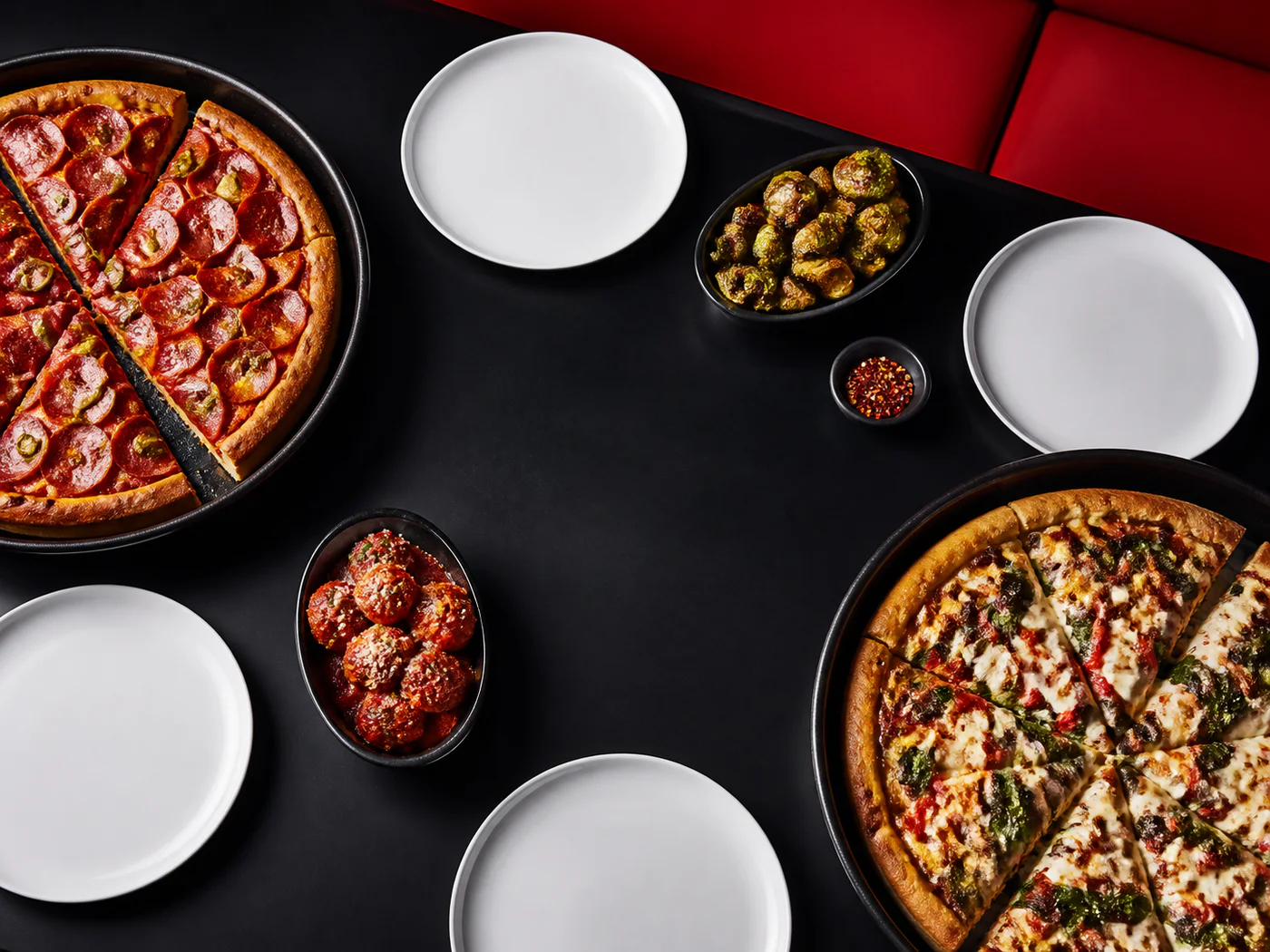 Zwei Pan Pizzas und Beilagen auf einem gedeckten Tisch